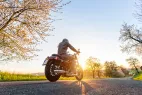 Un motard de dos qui roule sur une route ensoleillée