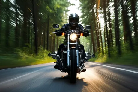 Un homme sur une moto conduisant sur une route bordée d'arbres